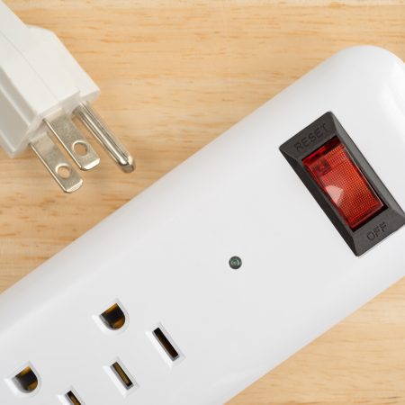 Top close view of a household surge protector on a wood table top.